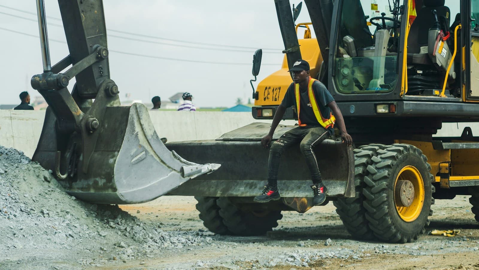 Nigerian road construction site with an excavator and a site worker